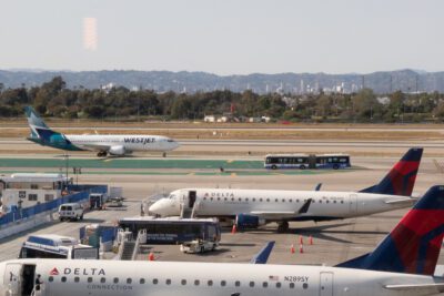 A WestJet plane taxis past Delta planes at LAX